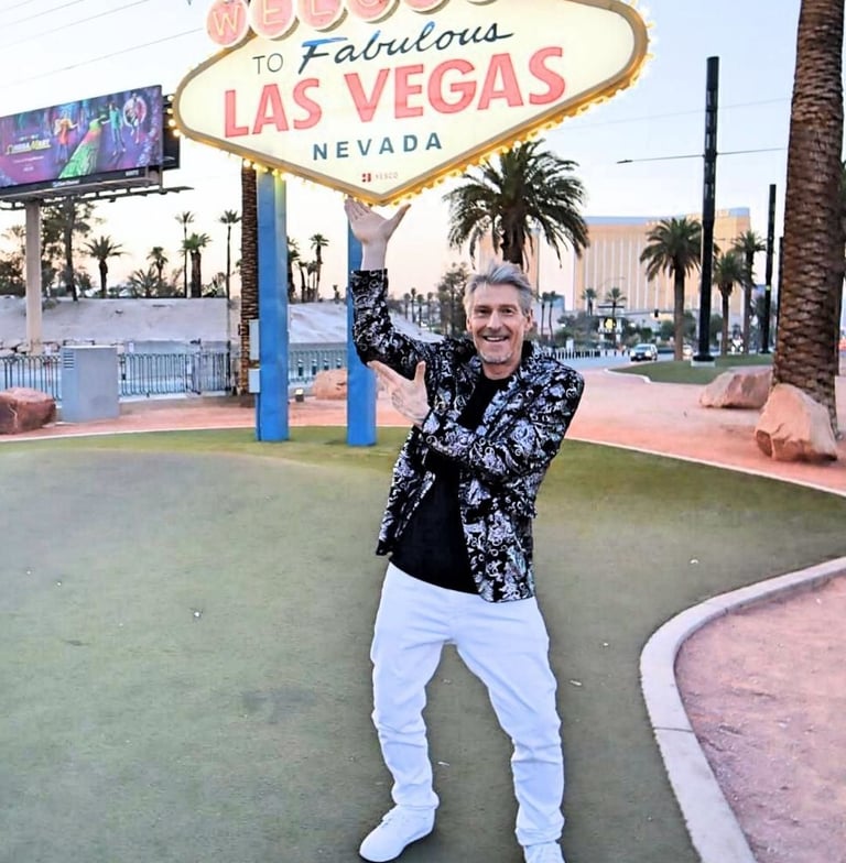Tim in a floral blazer posing in front of the iconic Welcome to Fabulous Las Vegas Nevada sign.