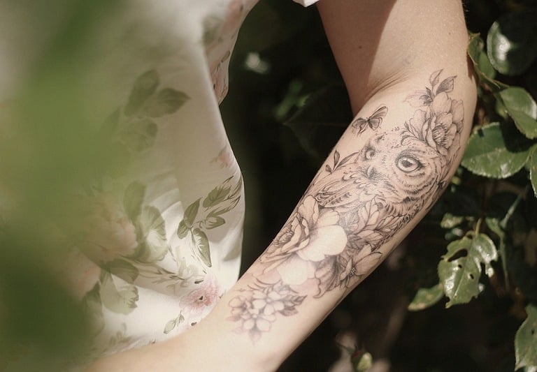 Une femme avec un tatouage sur le bras chouette hiboux