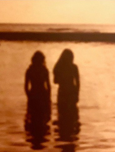 Silhouettes of the backs of Nancy Jo and her best friend, Debbie, standing in the ocean in Kauai