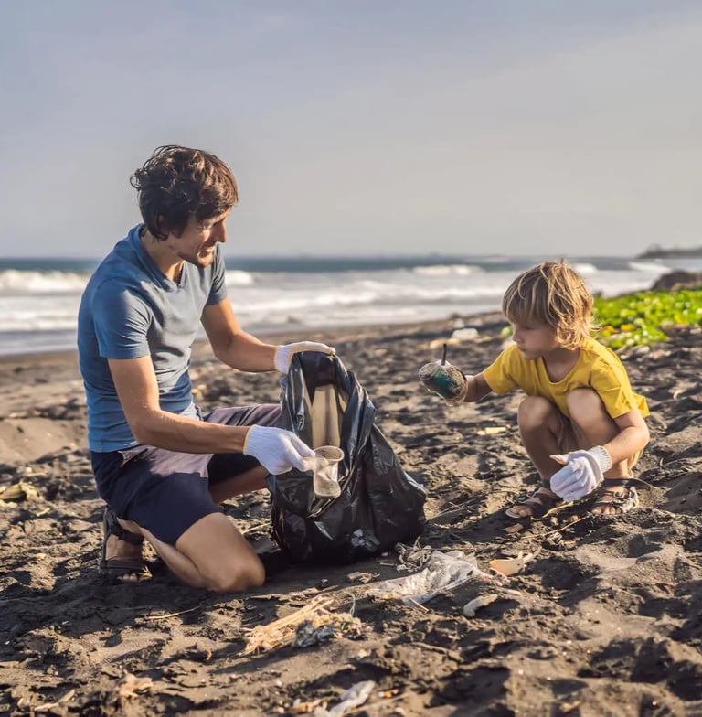 A father and his son sitting on the beach, collecting garbage into a black plastic bag