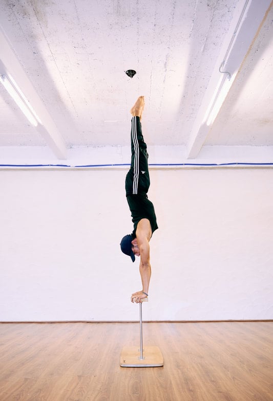 Man voert een rechte handstand uit op canes bij De Polecats Fabriek in Gent