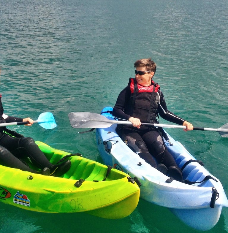 Two kayakers side by side with deep green sea