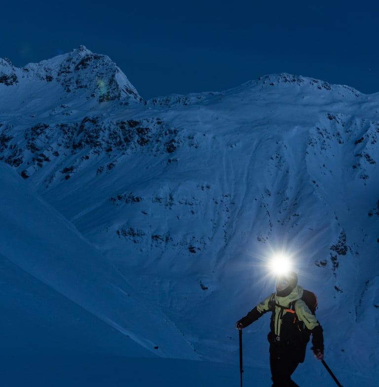 Ski touring skier wearing a Silva headlamp at dawn in alpine terrain