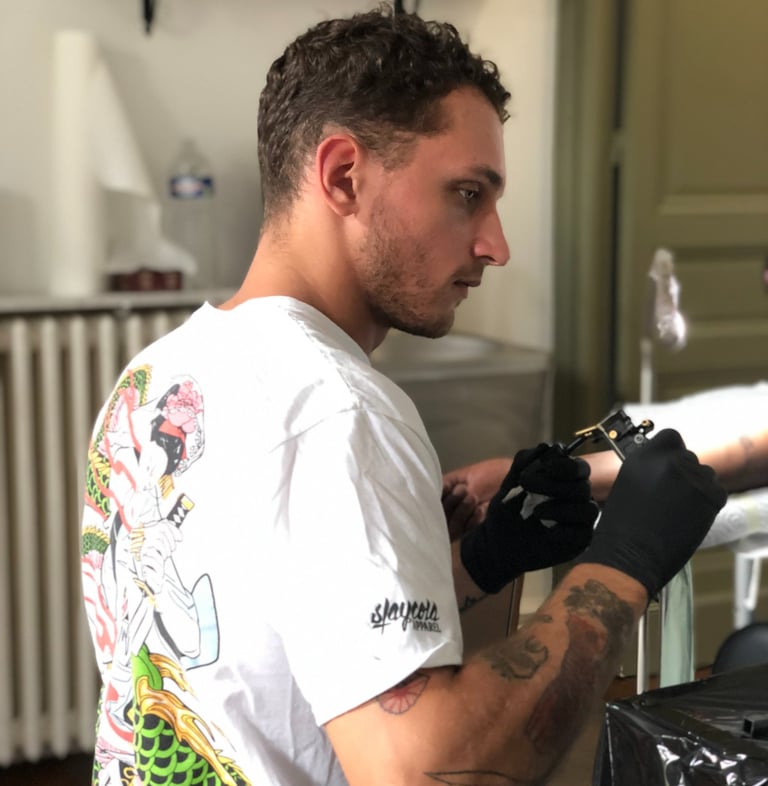 Jeune tatoueur entrain de tatouer