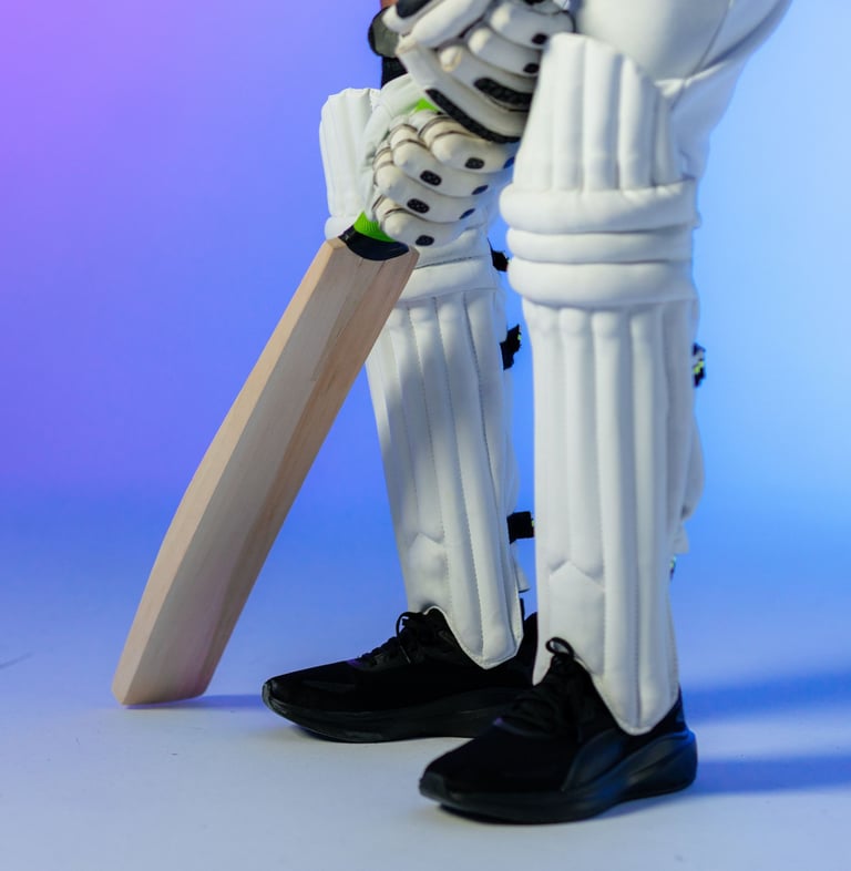 showing man's legs and hands holding cricket bat and wear pads and black running shoes