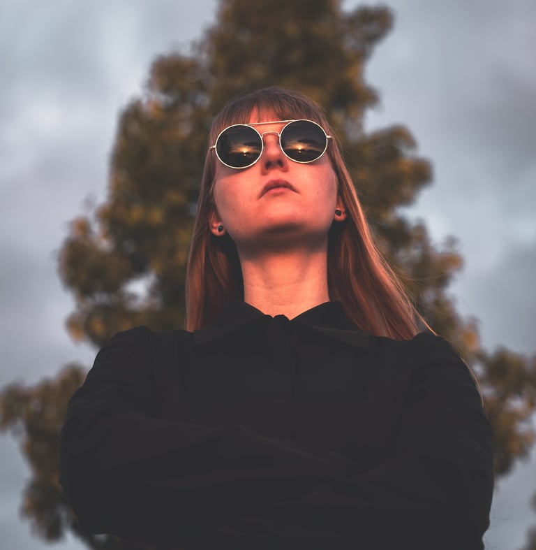 a women in a black jacket and sunglasses staring into the sunset