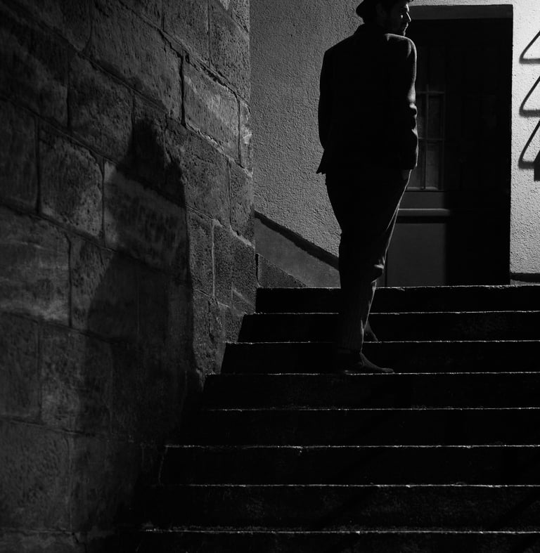 a man in a hat and a suit jacket is walking up stairs