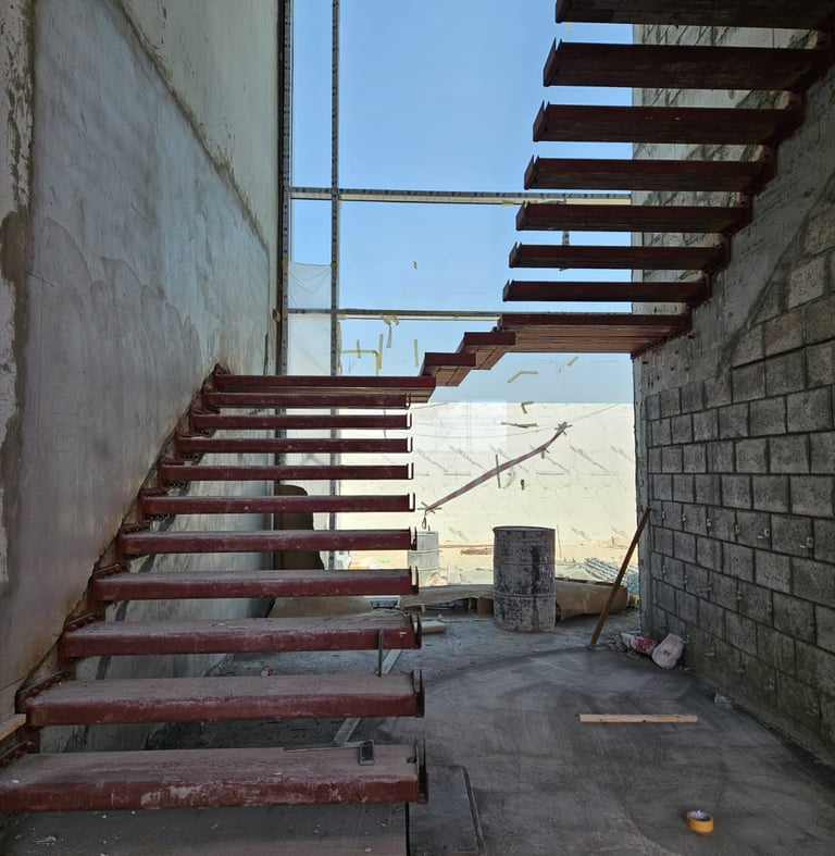 Custom steel staircase structure under fabrication on-site at UAE construction project.