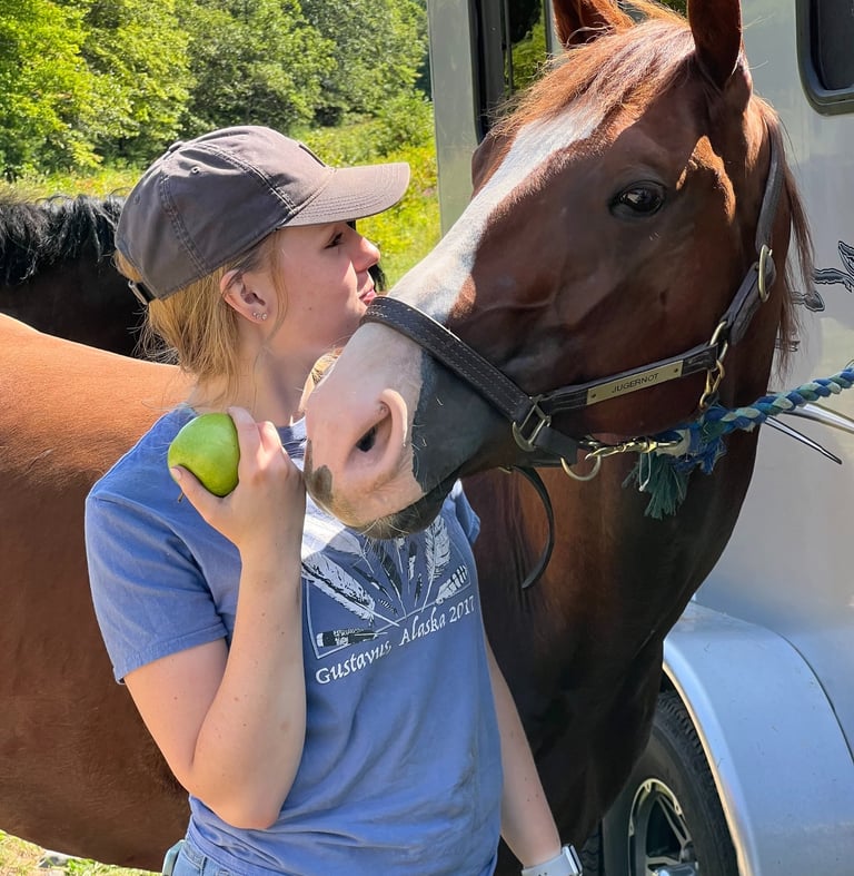 a woman in a hat and a horse at a trailer