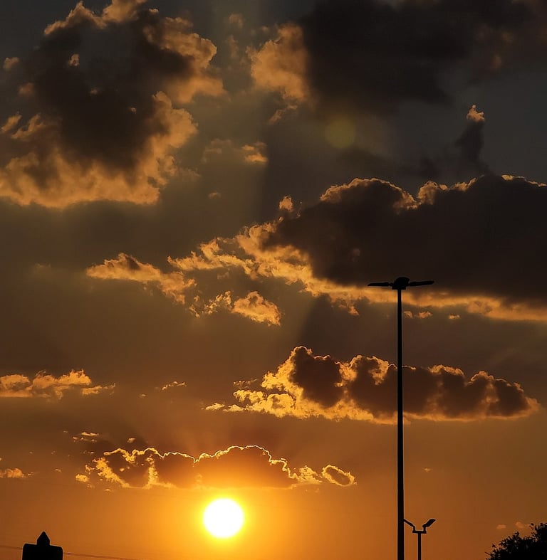 Yellow glowing sunrise with rays of sunlight shining through the clouds