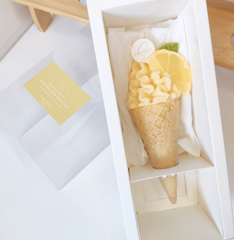 An ice cream-shaped soap inside a white box with lemon slice and mint leaf made of soap