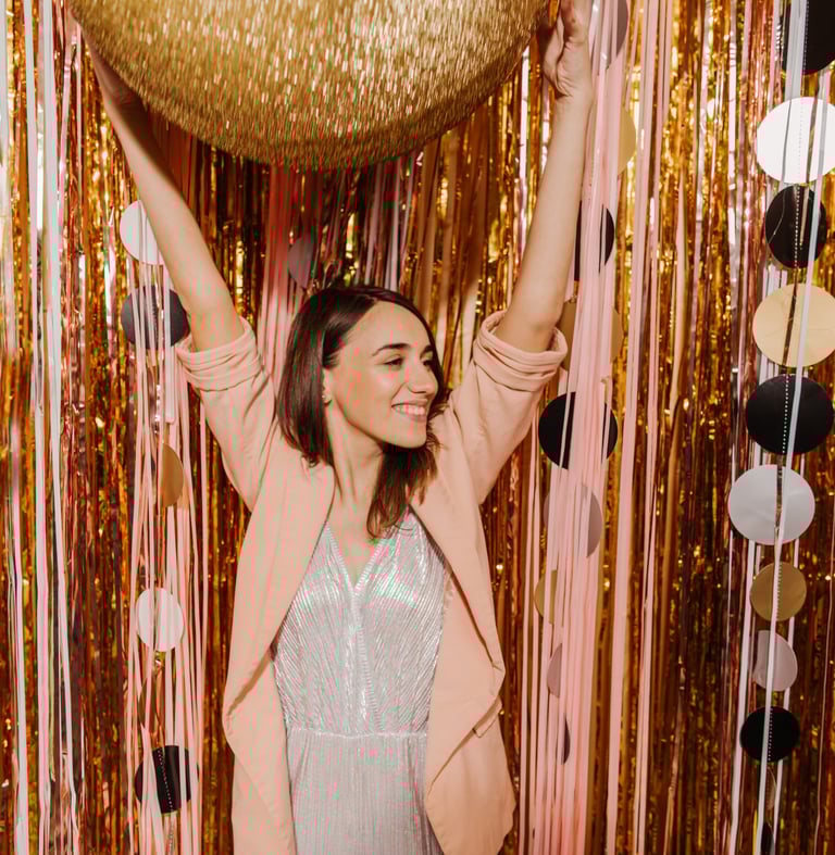 une femme vêtue d'une robe argentée et d'un ballon doré Se fait prendre en photo par un Photo Booth 