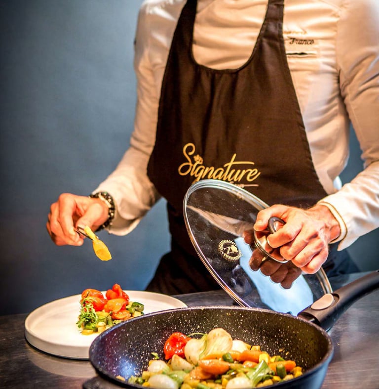 A man in a chef's apron preparing food using Napoleon Imperial Stone Noire cookware