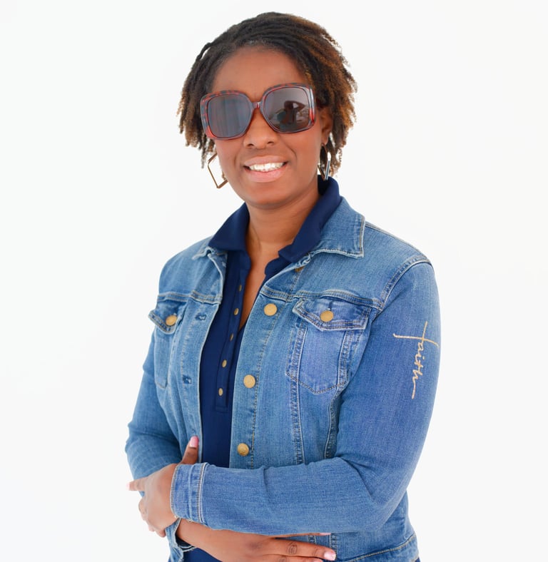 Smiling woman with jean jacket and shades with arms crossed