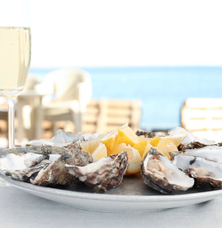 Huîtres ouvertes posées à côté de 2 flûtes de Champagne remplies