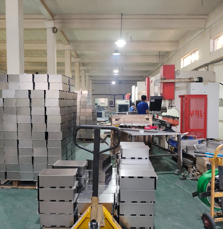 Pallet jack moving stacked stainless steel enclosures in a precision metal fabrication factory.