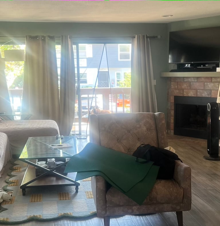 before staging: a clutered room with chair, copy table and sofa. fireplace and wood ladder