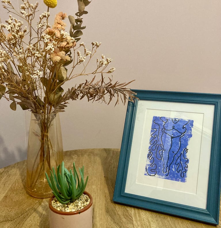 Photo of a table, with flowers and a framed illustration