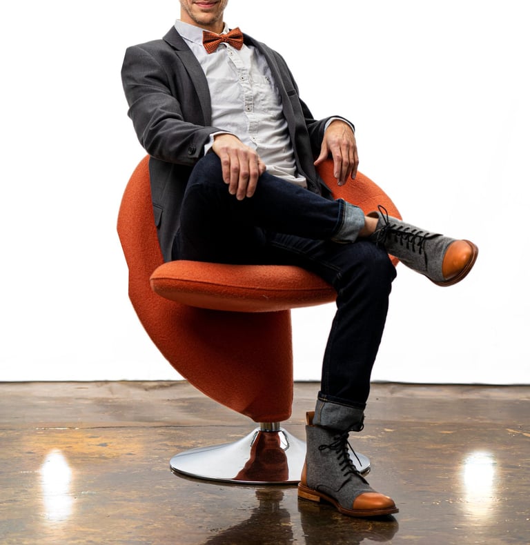 Remy sits in a chair wearing a sportcoat and bowtie