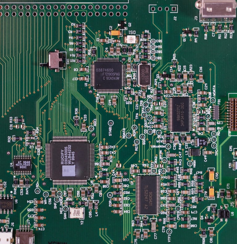 A forest green square computer motherboard with circuits, sockets, and processors on its surface.