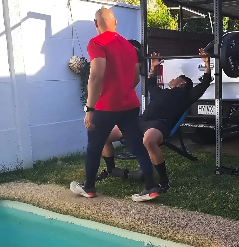 Cliente en press de banca inclinado con su personal trainer en Las Condes.