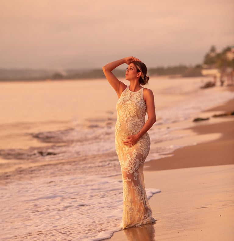 una mujer embarazada en la playa, viendo el atardecer