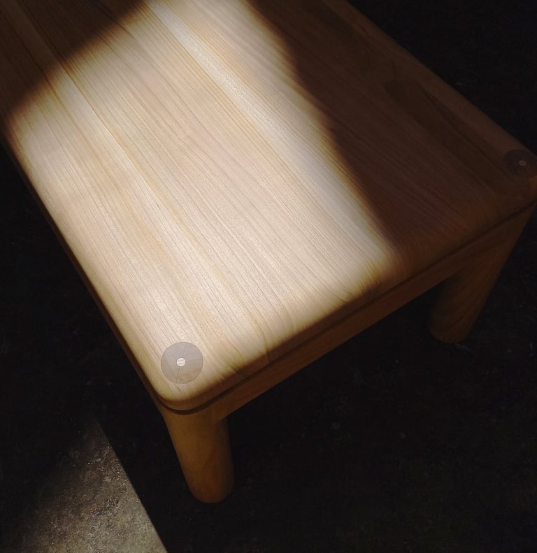 table basse en merisier aux angles et arêtes arrondis dans un rayon de soleil