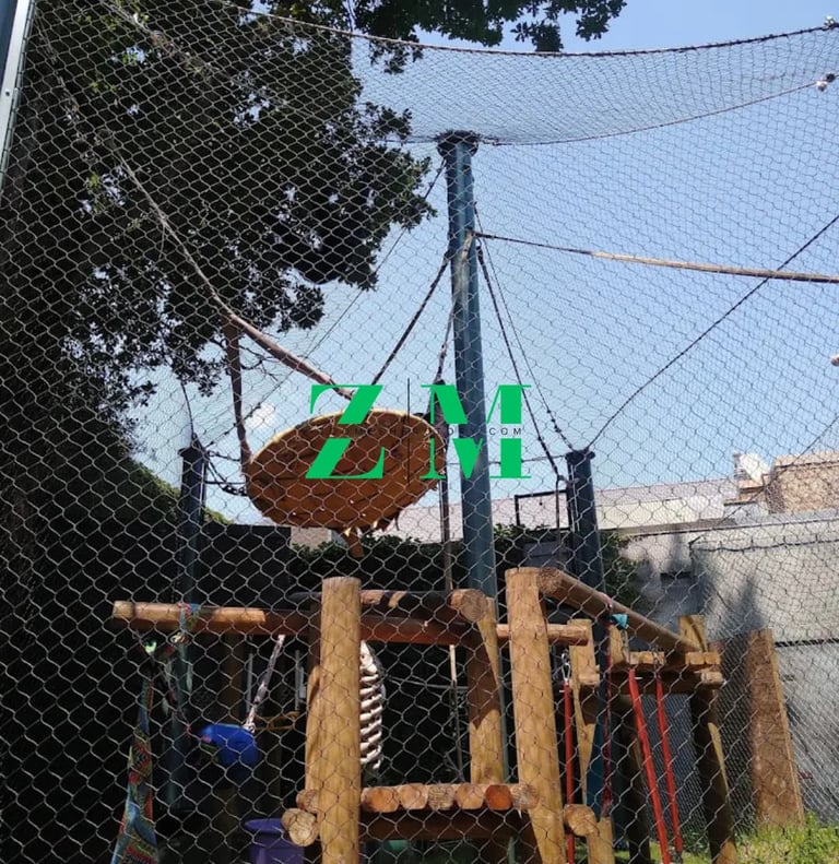 An outdoor rope climbing structure with safety netting and tire swings for playground activity.