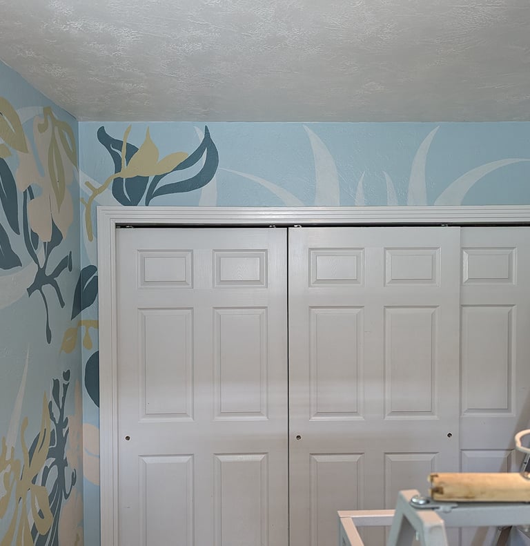 Using soft colors to layer multiple flower shapes on a large mural surrounding a closet.