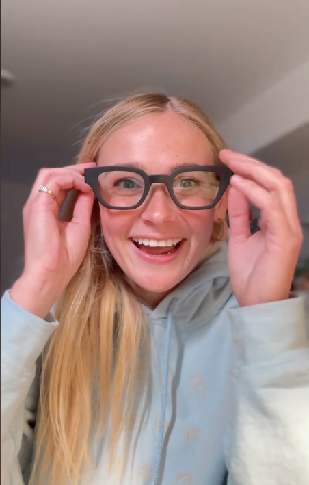 una chica sonriente poniéndose unas gafas