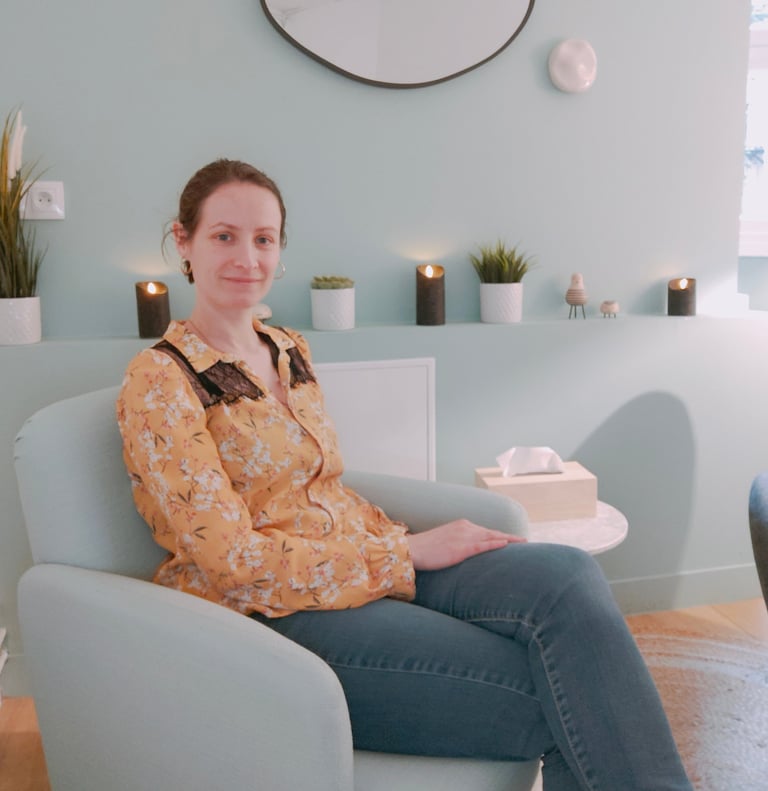 Une hypnothérapeute assise sur un fauteuil dans un cabinet d'hypnothérapie et un miroir sur le mur