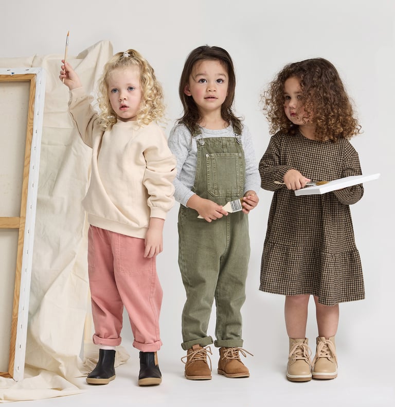 Fashion photography - three young children standing in front of a white canvas
