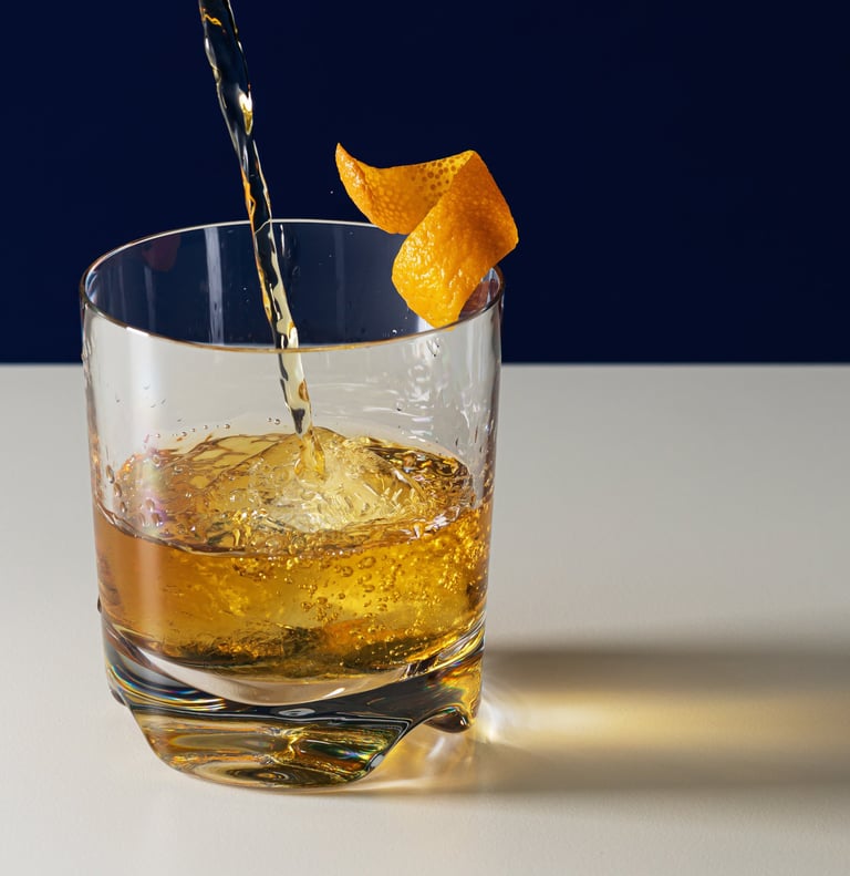 Product photography - whiskey being poured into a glass with an orange peel