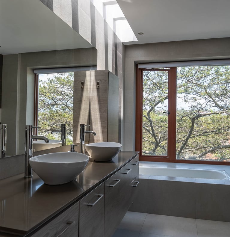 fotografía inmobiliaria quito ecuador tumbaco baño elegante y sobrio con dos lavabos y vista a un árbol