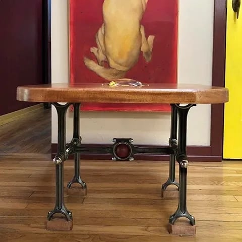Industrial coffee table made of wood top and base made of engine rods.