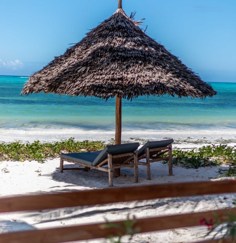 a beach umbrella with two sun bed at Villa Serene Zanzibar 