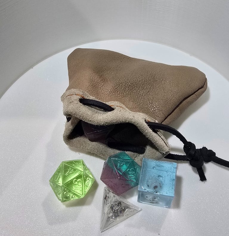 Colorful translucent resin dice spilling out of a handcrafted leather dice bag.