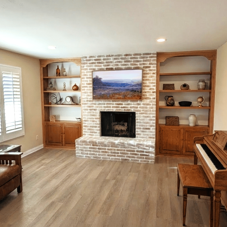 Living room with white brick fireplace, built-in wooden bookshelves, upright piano, and leather recliner.