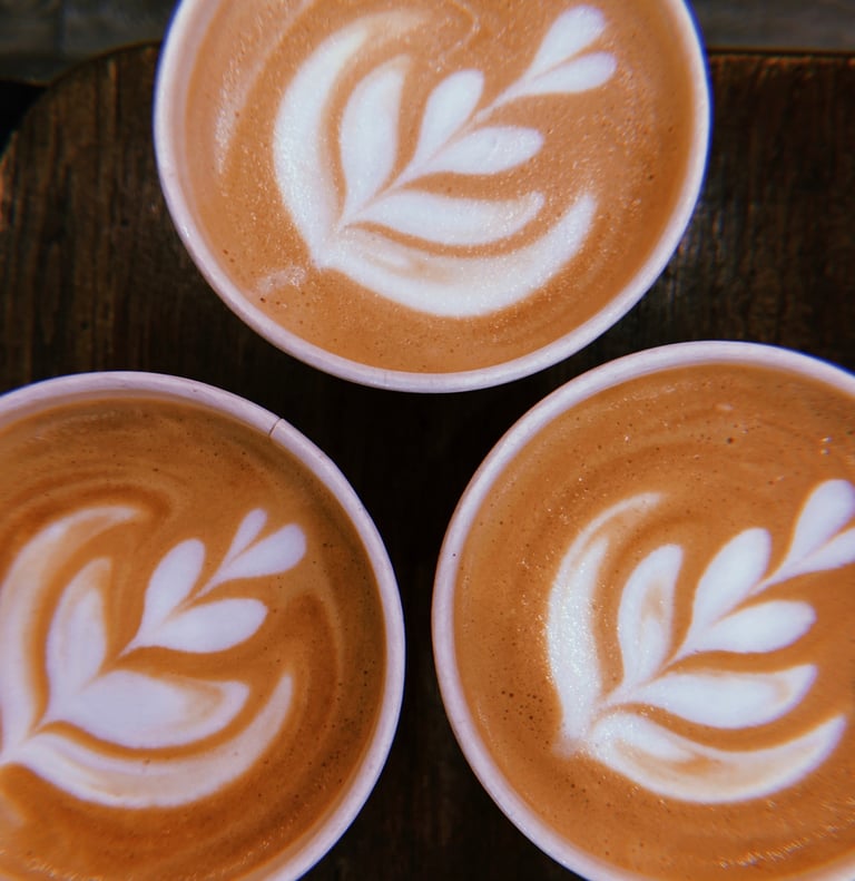three cups of coffee with a leaf design on the bottom
