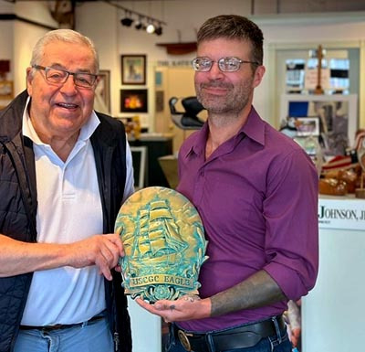Picture of artist Matt Heft holding a USCGC Barque Eagle custom plaque with Thames River Gallery owner. John Johnson