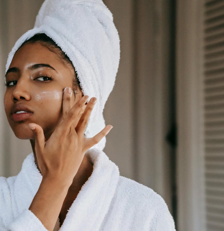 A woman is rubbing moisturizer into her cheek.
