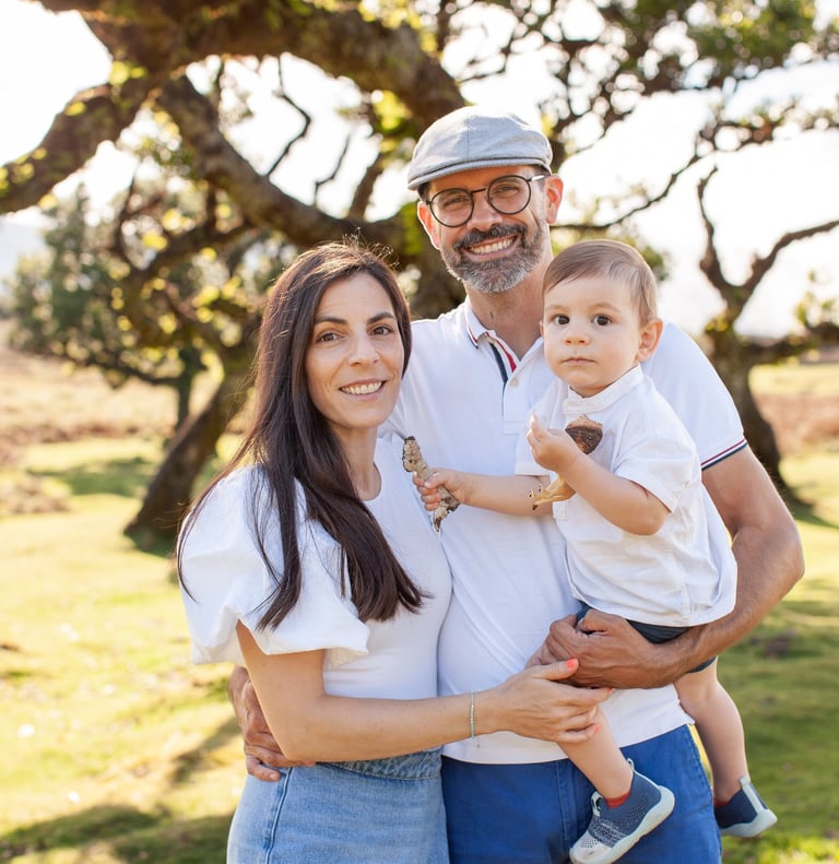 Toddler son standing between mother and father during outdoor family photography session at Fanal Fo
