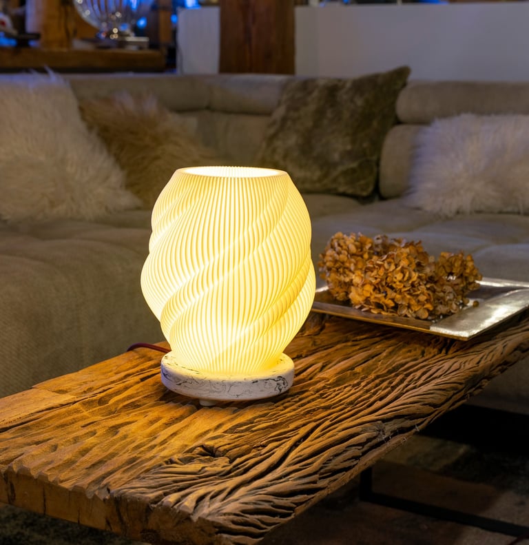Modern 3D printed table lamp with warm glow on a rustic reclaimed wood coffee table.