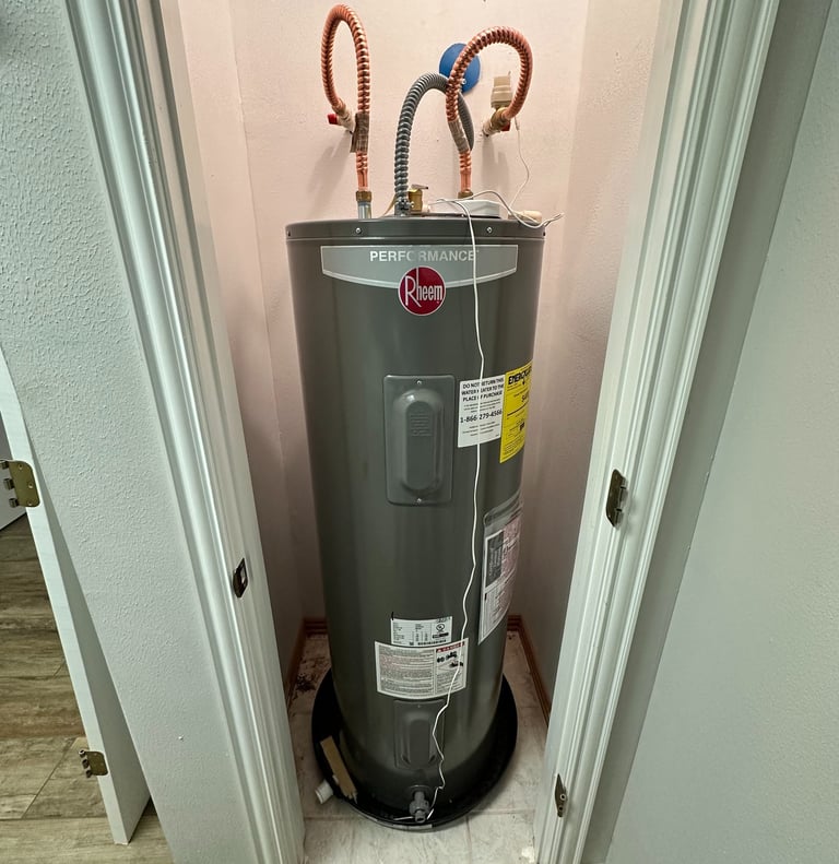 Rheem Performance electric water heater installed in a residential utility closet with copper piping.