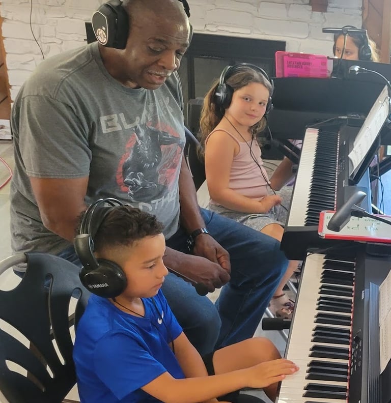 a group of kids sitting at pianos with a teacher