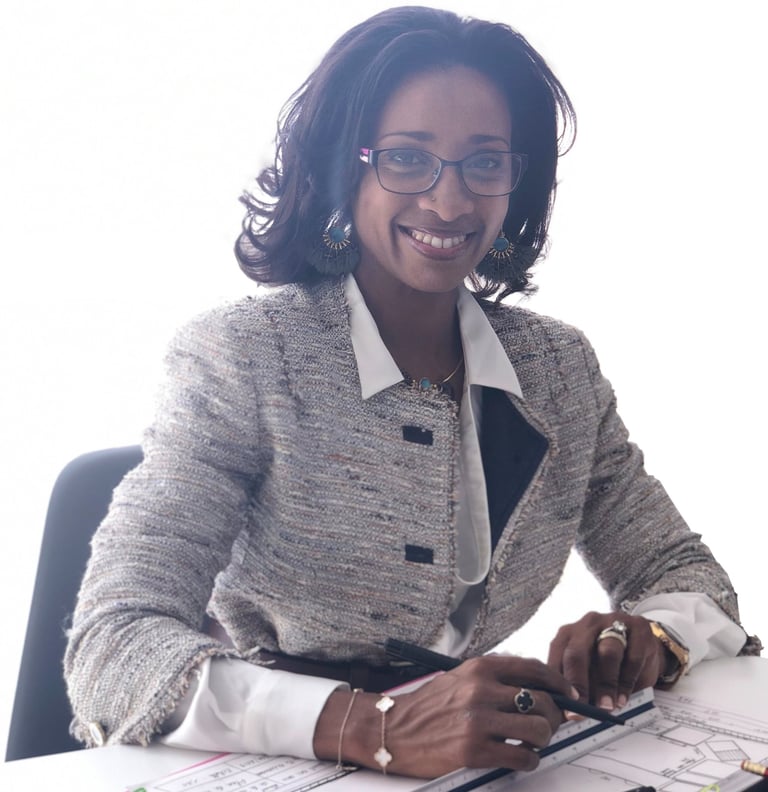 Smiling professional female architect in a blazer working on blueprints at her office desk.