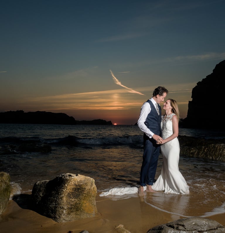 a bride and groom standing in the ocean