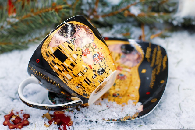 aza de café y plato con el estampado de la pintura "El Beso" de Gustav Klimt, colocados sobre nieve 