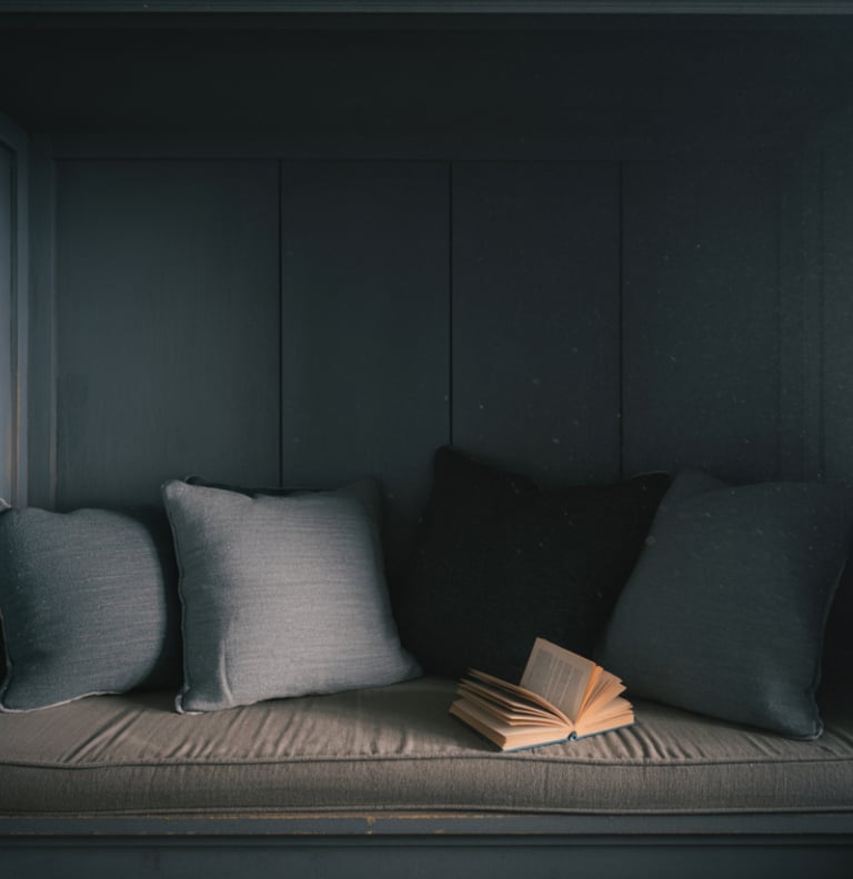 An over-decorated bench nook crowded with pillows and wall decor, cluttered feel.