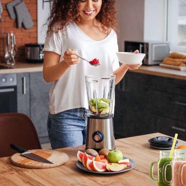 a woman is standing in front of a blender
